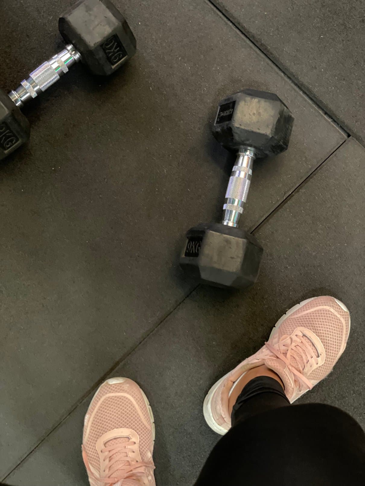 Dumbbells and pink trainers on a gym floor