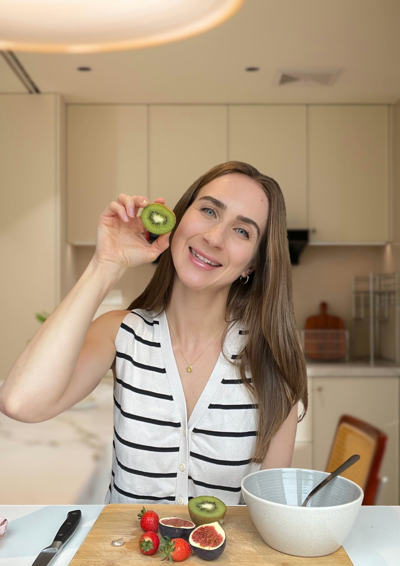 Rosie holding half a kiwi in her kitchen